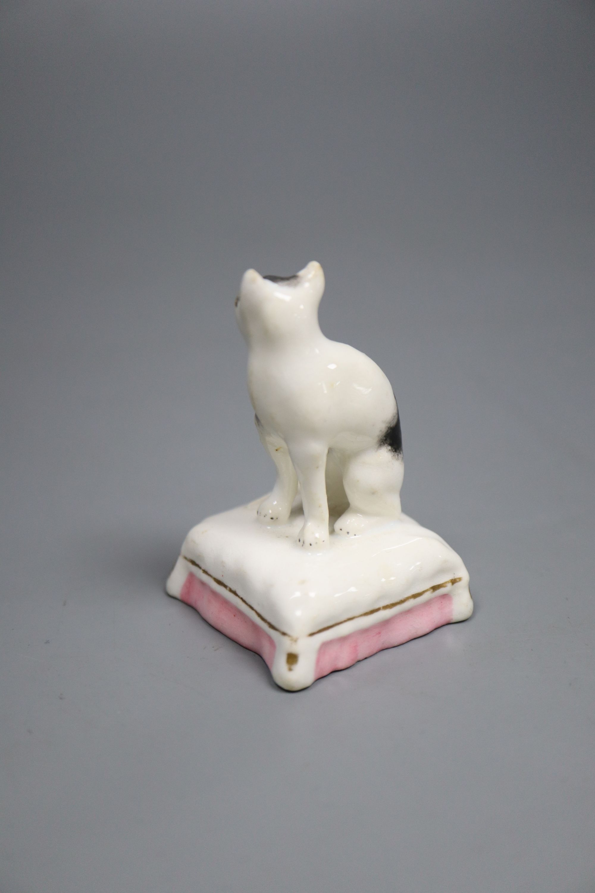 A rare Staffordshire porcelain figure of a cat seated on a cushion, c.1835-50, 6cm